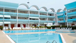Ein Hotel mit mehreren Schwimmbecken, Liegestühlen und einem mehrstöckigen Gebäude mit Balkonen.