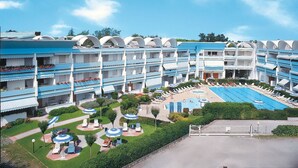 Een meerlaags hotel met een centraal gelegen zwembad, buitenzitplaatsen en een verzorgde tuin.