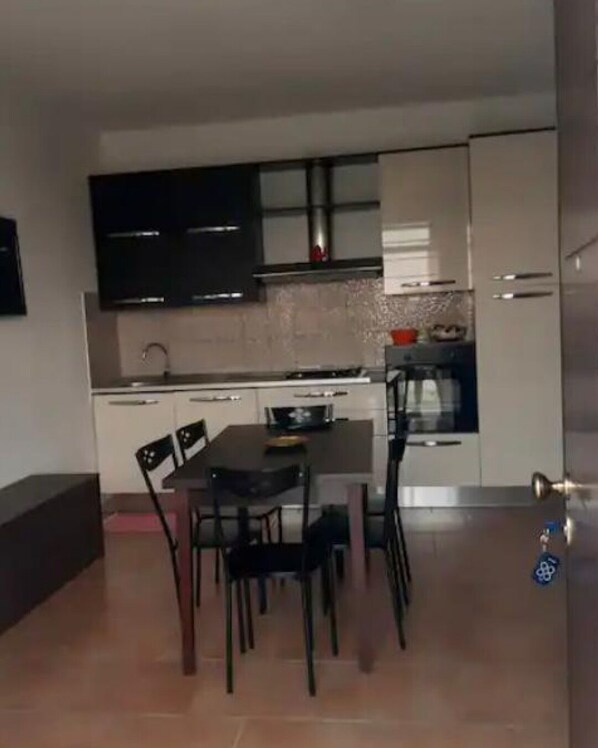 A compact kitchen with a dining table and chairs, a built-in oven, and a microwave.