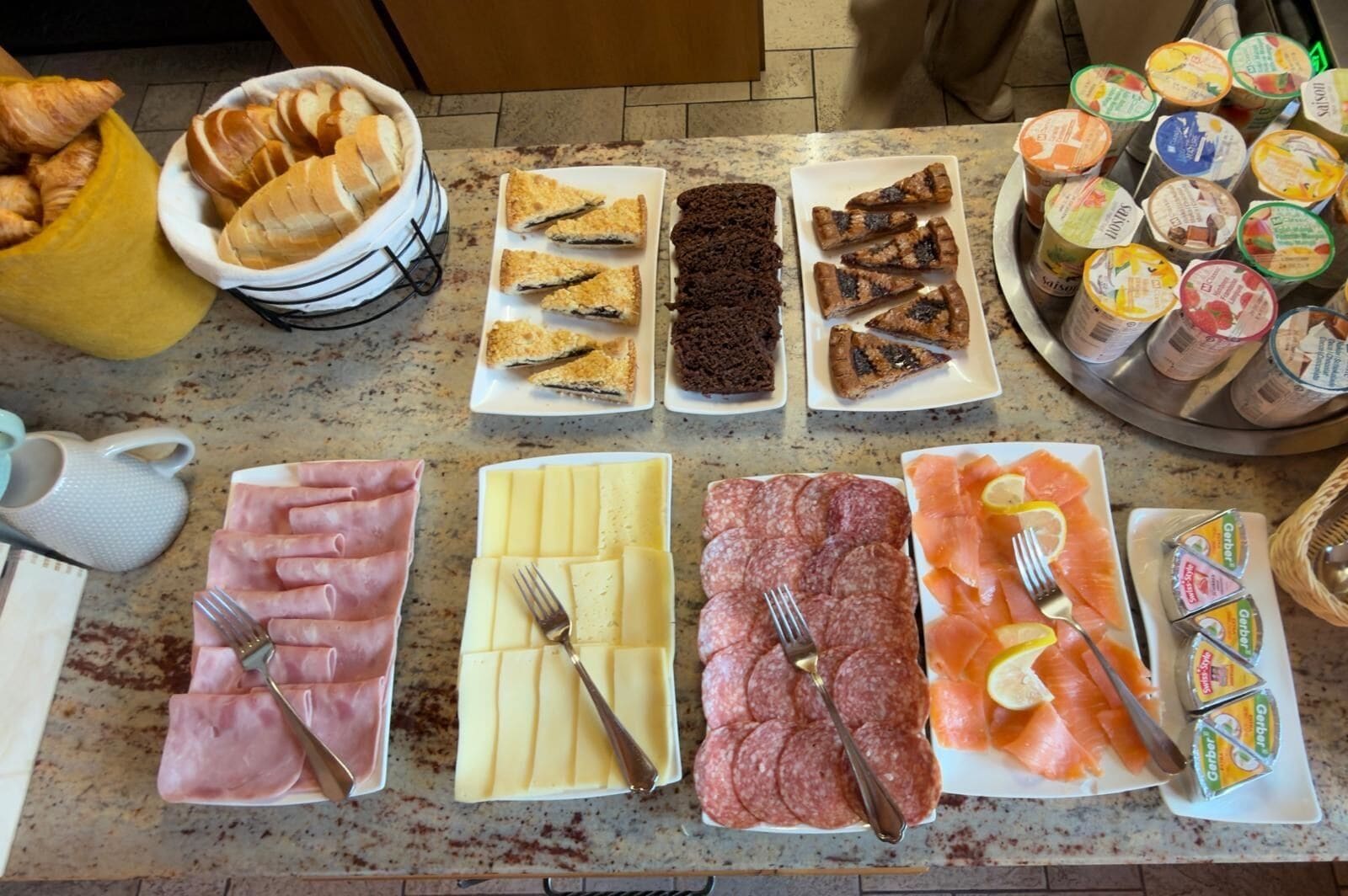 A breakfast buffet with various food items including pastries, meats, cheeses, and spreads.