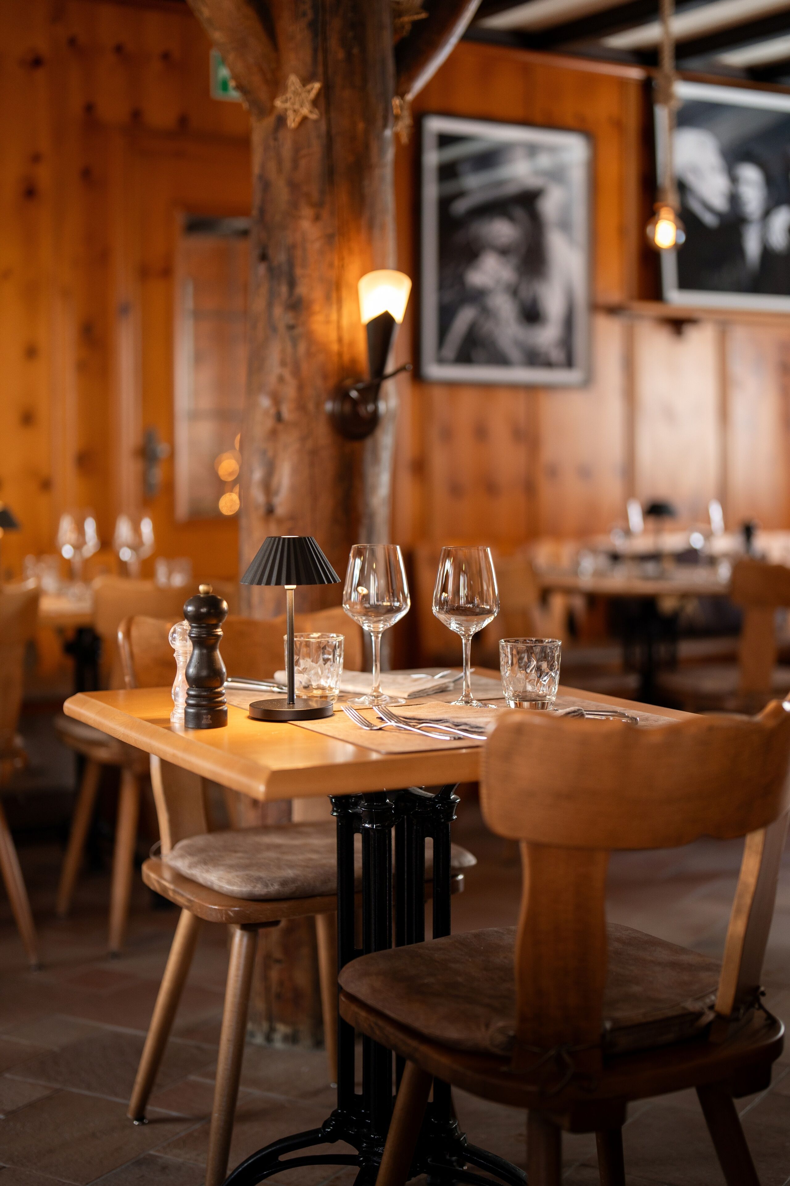A restaurant interior with wooden tables, chairs, and a central lamp.