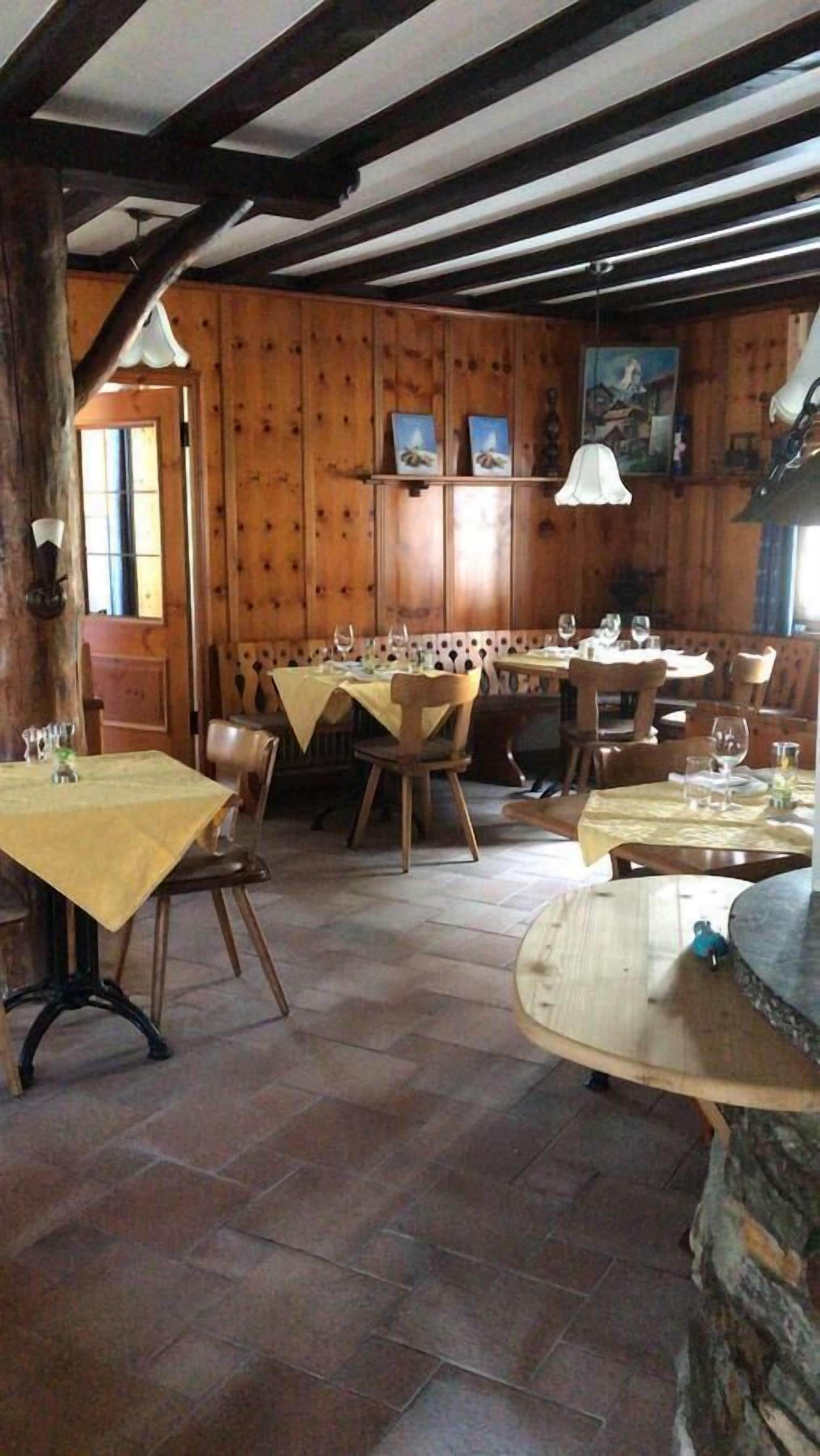 Un interior rústico de madera con varias mesas de comedor, sillas y una chimenea de piedra.