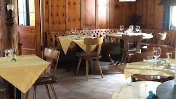 Un interior rústico de madera con varias mesas de comedor, sillas y una chimenea de piedra.
