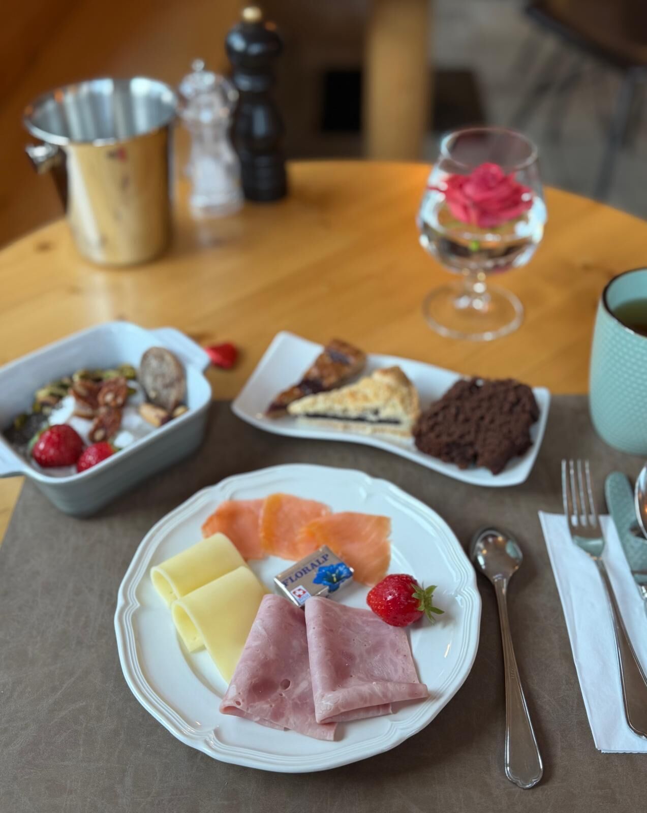 A table with various food items including cheese, ham, salmon, and strawberries.