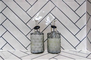 Two glass bottles with black caps on a tiled surface. - LidaPoolVilla ChiangMai (San Sai)