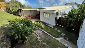 A small house with a patio, a wooden deck, and a covered seating area. - Martinique Villa Escale Diamant (Le Diamant)