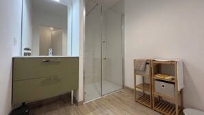 Ein modernes Badezimmer mit Duschkabine aus Glas, einem Holzwaschtisch mit Stauraum und einer Toilette.