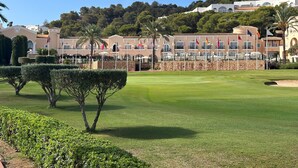 Un campo de golf bien cuidado con setos recortados y un cielo despejado.