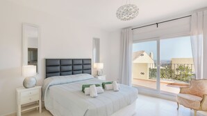Un dormitorio moderno con una cama grande, una mesita de noche, una lámpara y vistas al exterior.