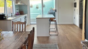 Una cucina moderna con isola centrale, tavolo da pranzo in legno e sgabelli da bar.