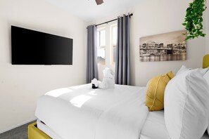 Relax in a stylish room with a large flat-screen TV, a comfortable bed, and a cityscape painting.