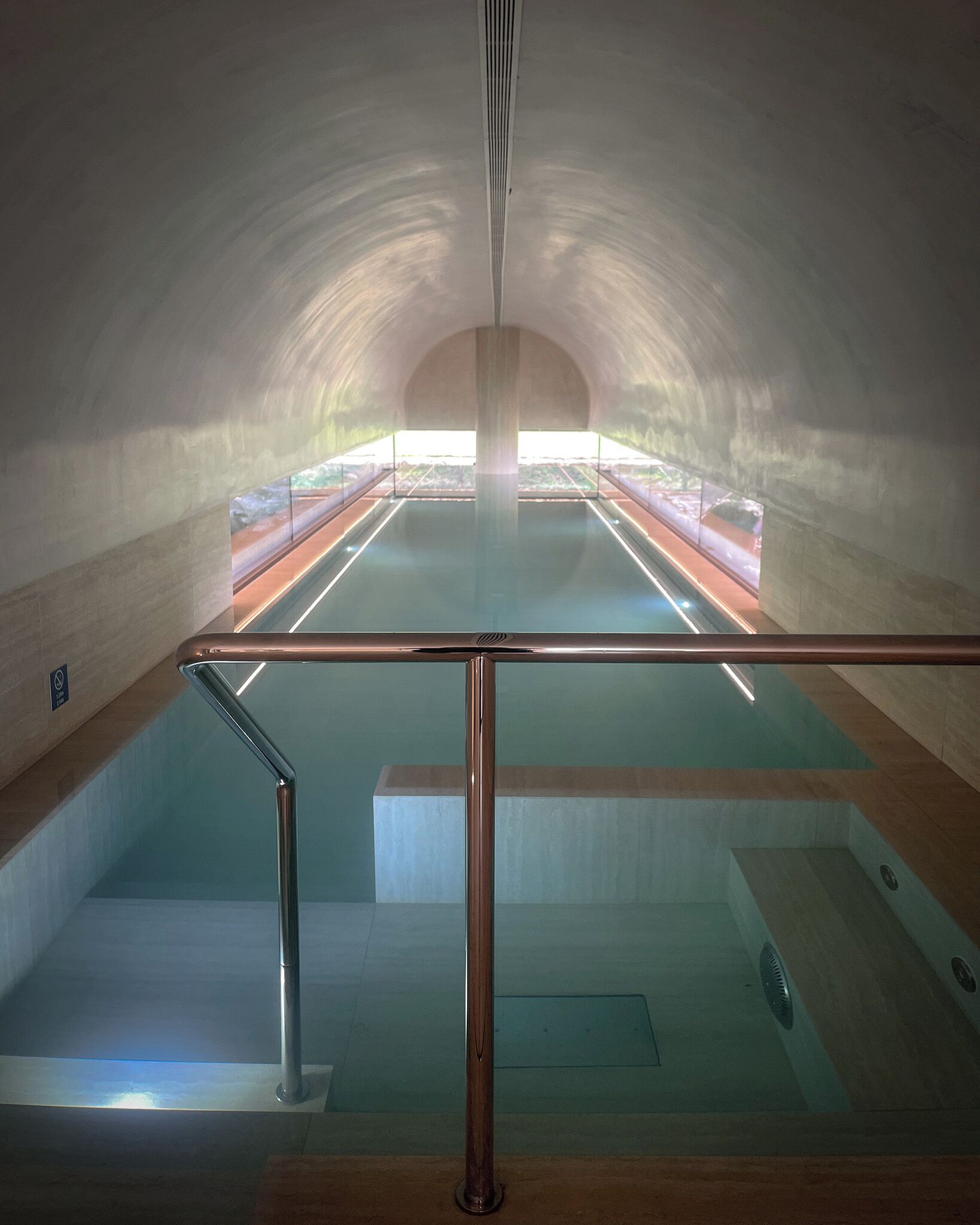 Una piscina interior con barrera de cristal y vistas al exterior.