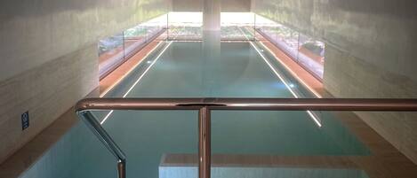 Una piscina interior con barrera de cristal y vistas al exterior.