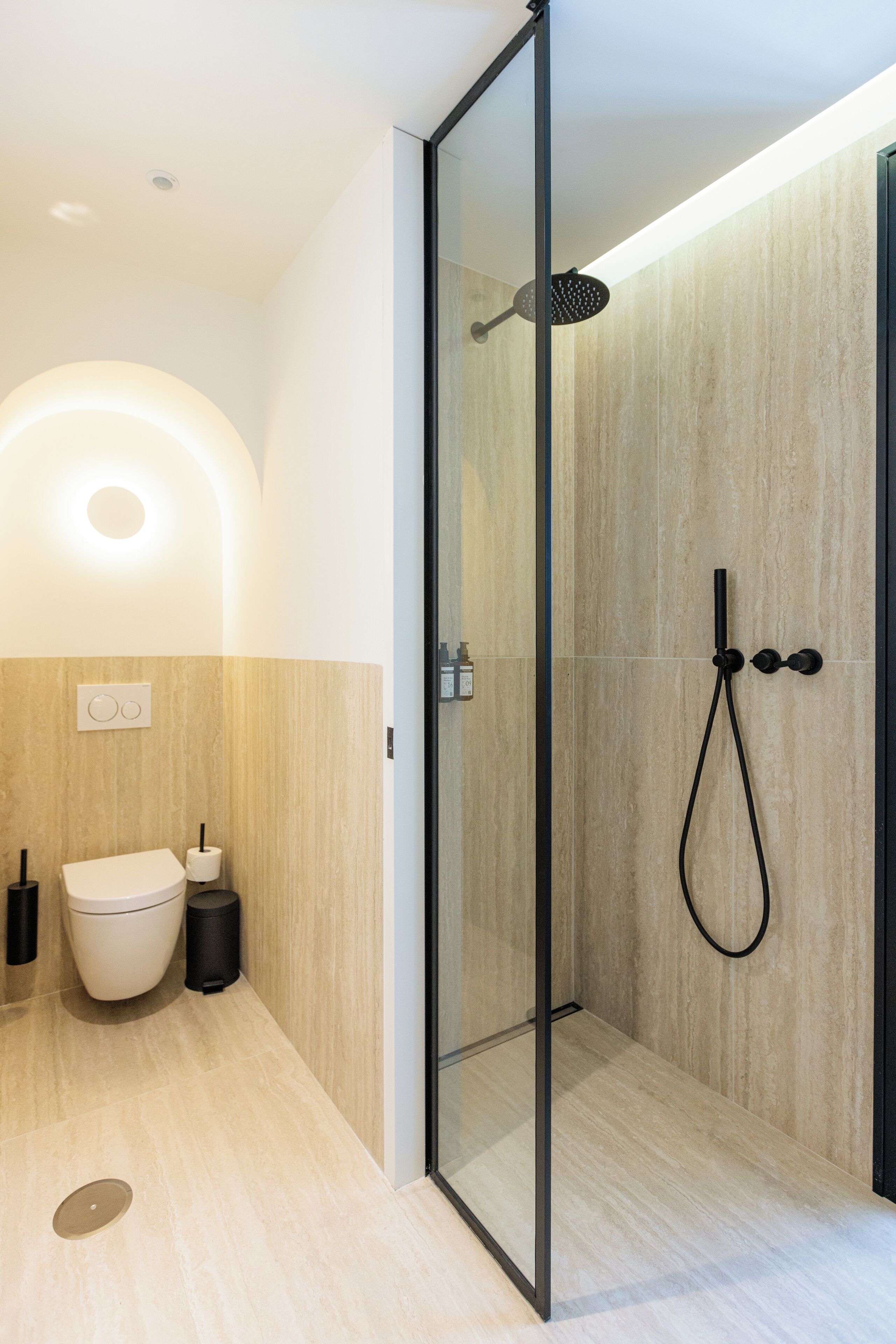 A modern bathroom with a glass-enclosed shower, a toilet, and a bidet.