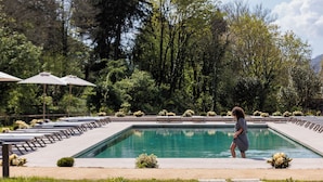 A swimming pool with lounge chairs and umbrellas, surrounded by greenery and trees. - MS Collection Arouca Mosteiro de Arouca (Arouca)