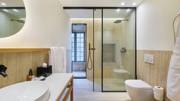 Un baño moderno con un lavamanos grande, inodoro y ducha con mampara de vidrio.