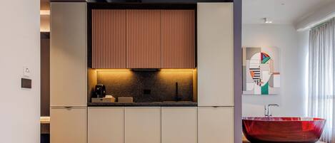 Una cocina moderna con una isla integrada, un lavamanos de vidrio rojo y una obra de arte contemporánea en la pared.