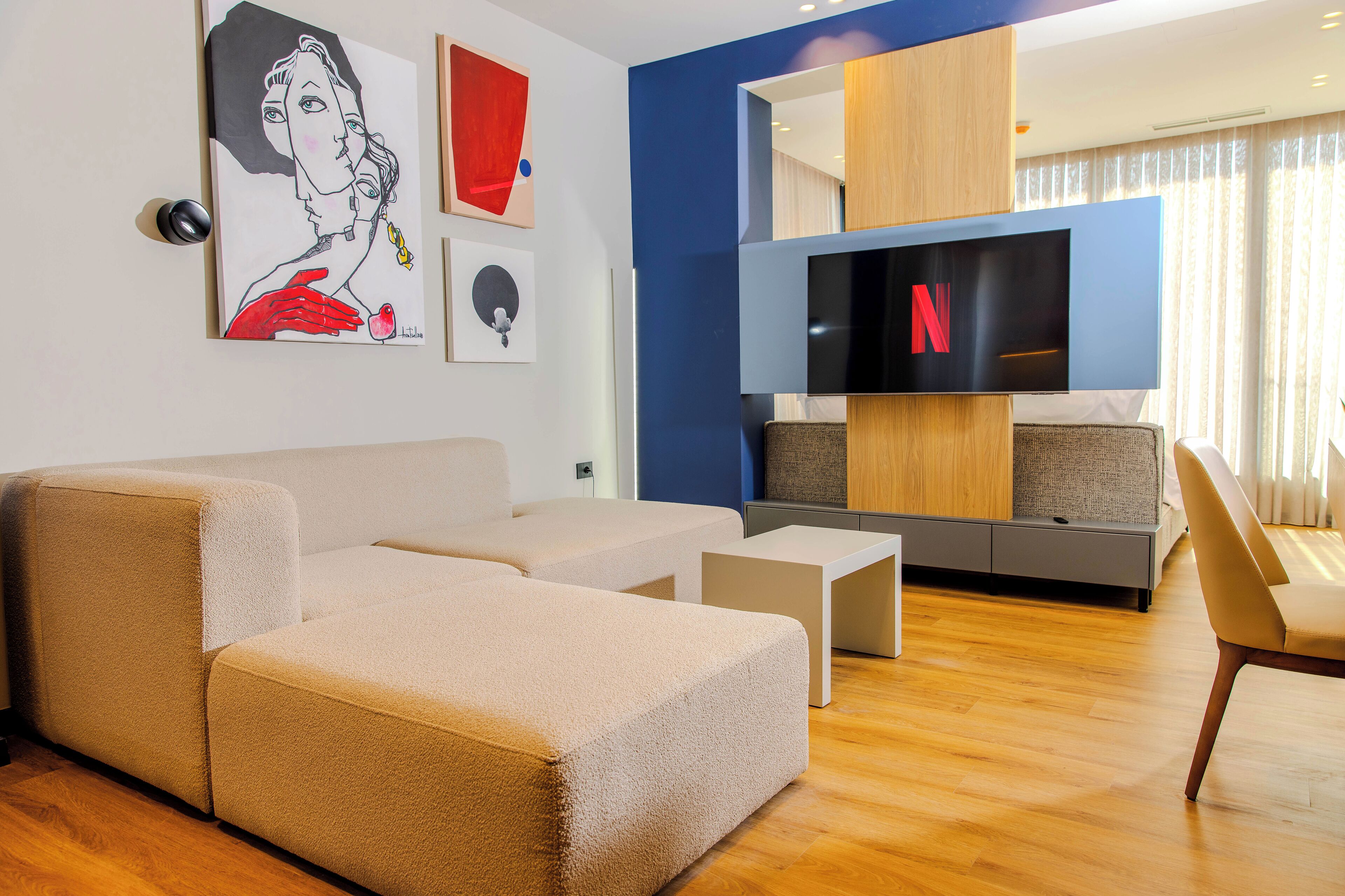 A modern living room with a sectional sofa, a flat-screen TV, and artwork on the wall.