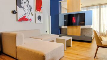 A modern living room with a sectional sofa, a flat-screen TV, and artwork on the wall.