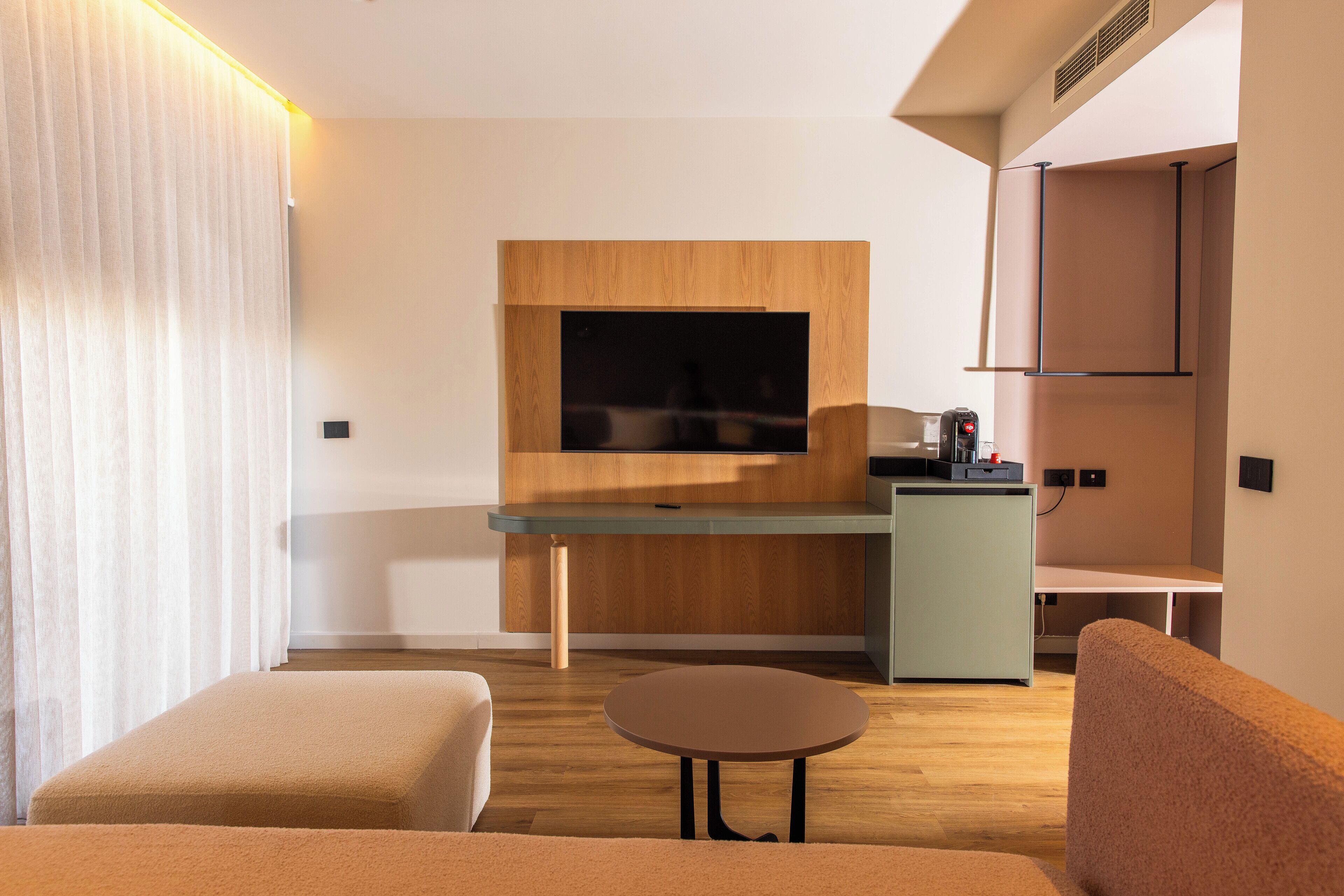 Un salon moderne doté d’un téléviseur à écran plat, d’éléments décoratifs en bois, d’une petite table ronde et d’un canapé.