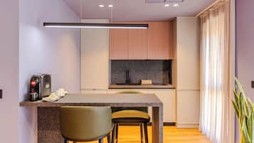 A modern kitchen with a central island, bar stools, and a coffee machine.