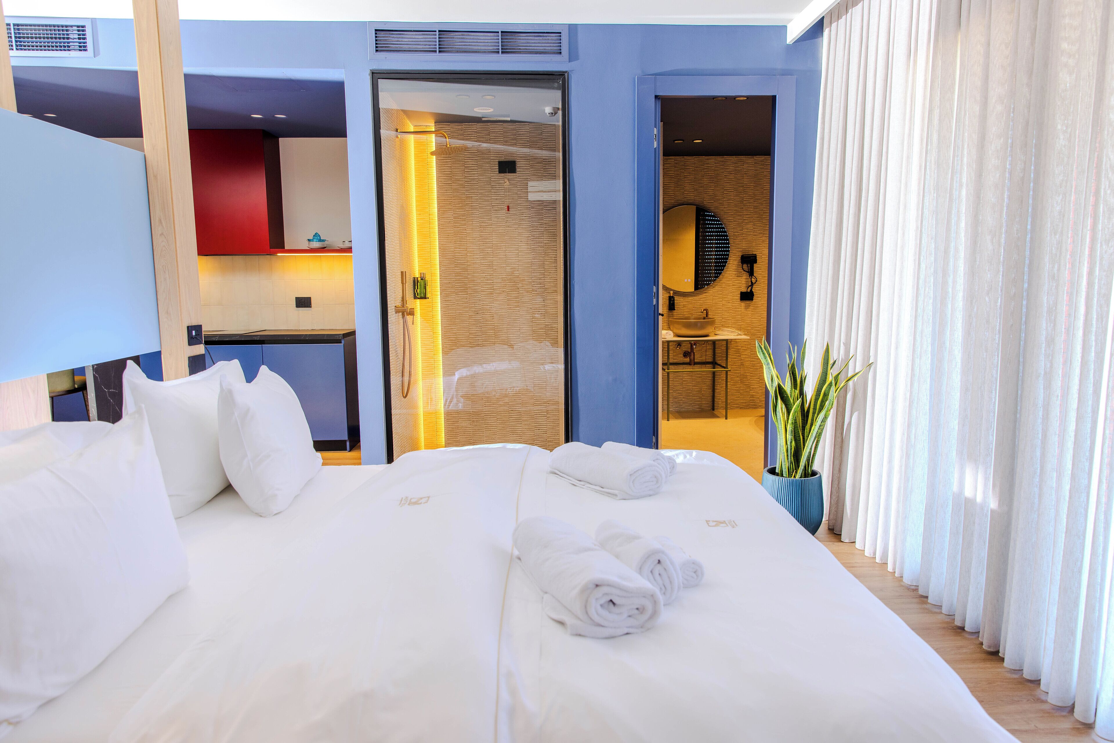 Et moderne hotelværelse med en stor seng, et badeværelse med et spejl og en potteplante.