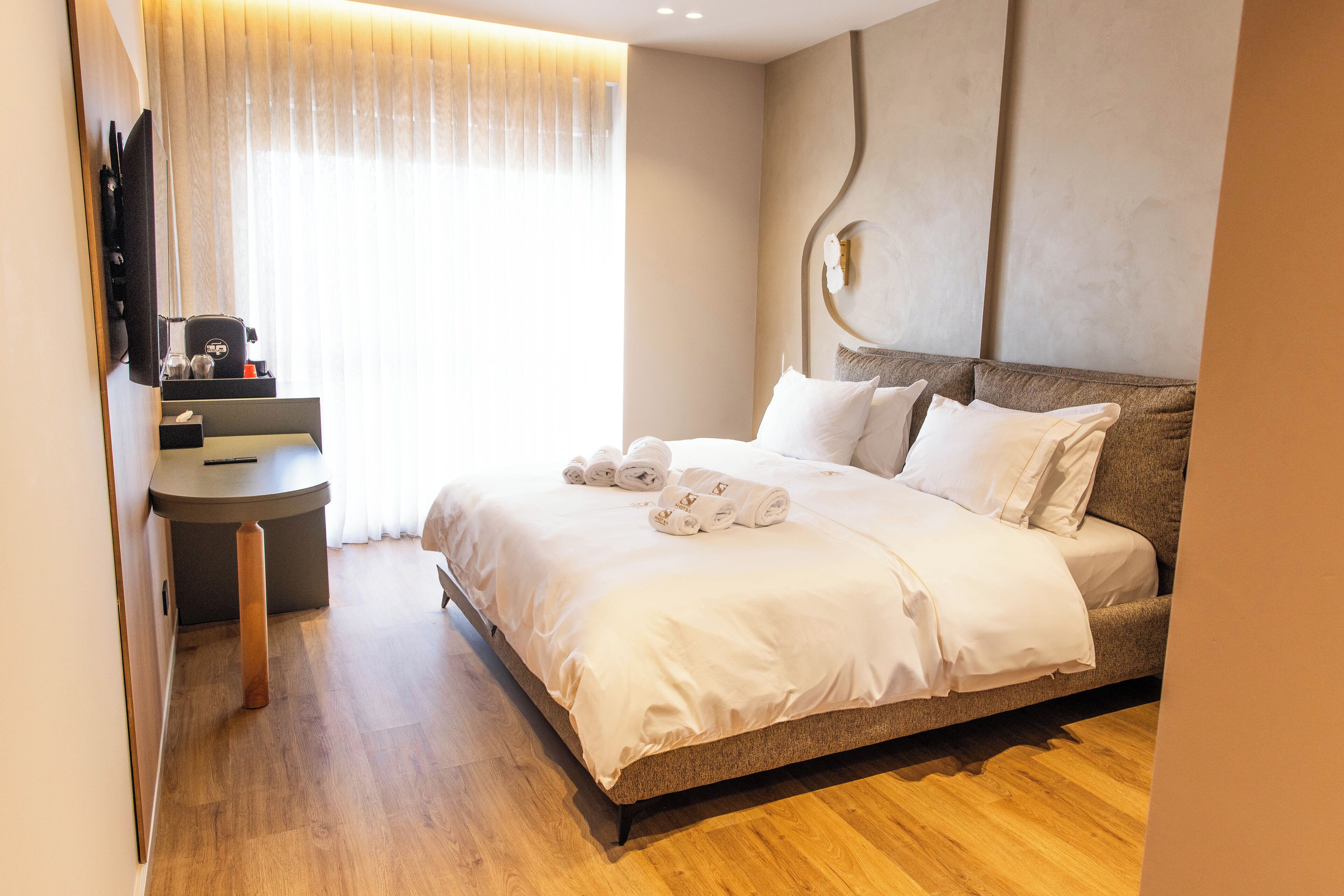 A hotel room with a bed, a desk, and a TV.