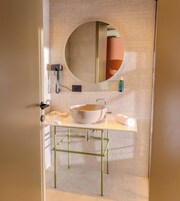 Un bagno con uno specchio tondo, un lavandino e un asciugamano sul ripiano.