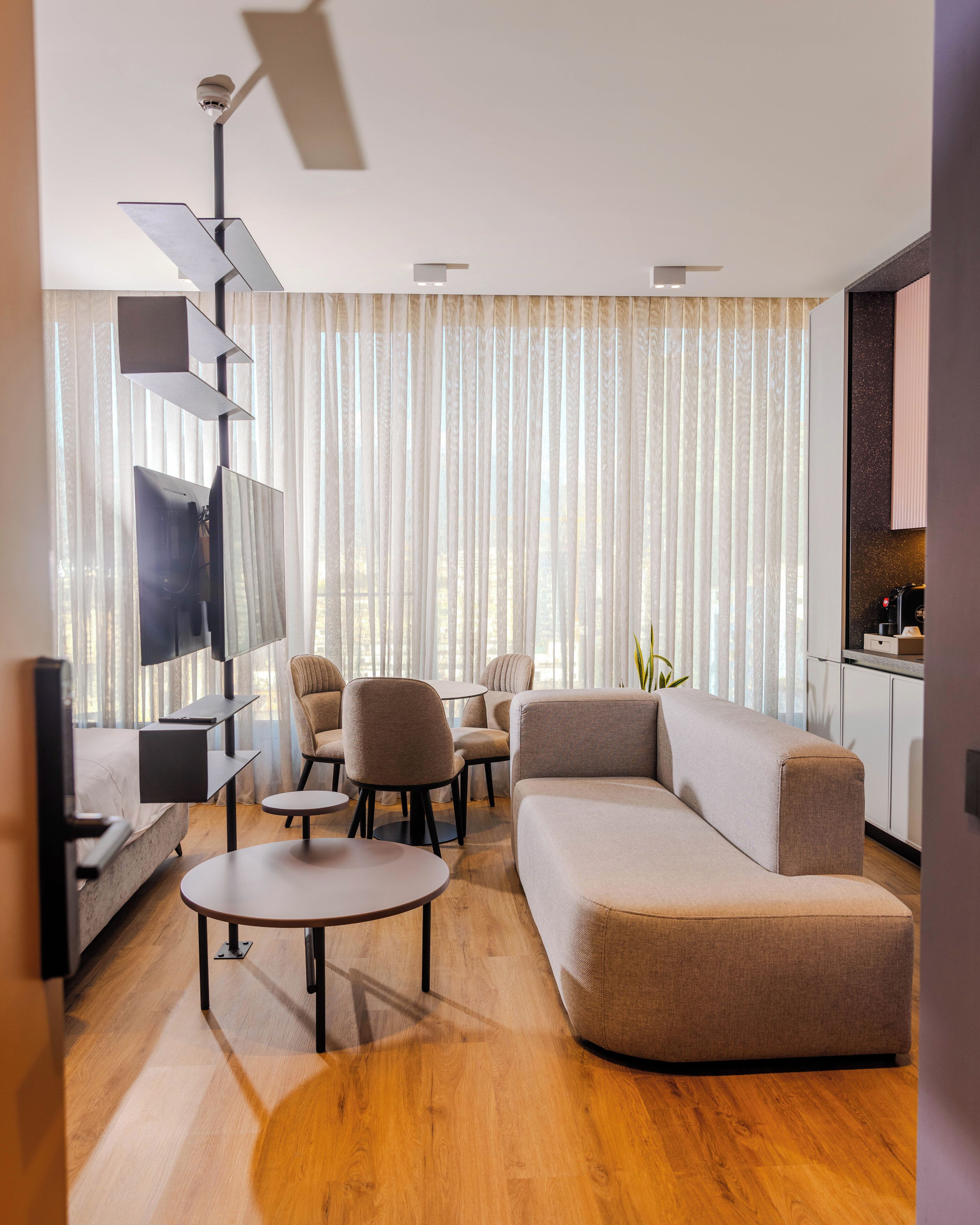 A modern living room with a sectional sofa, round coffee table, and a TV mounted on a wall.