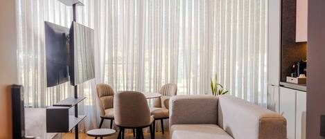 A modern living room with a sectional sofa, round coffee table, and a TV mounted on a wall.