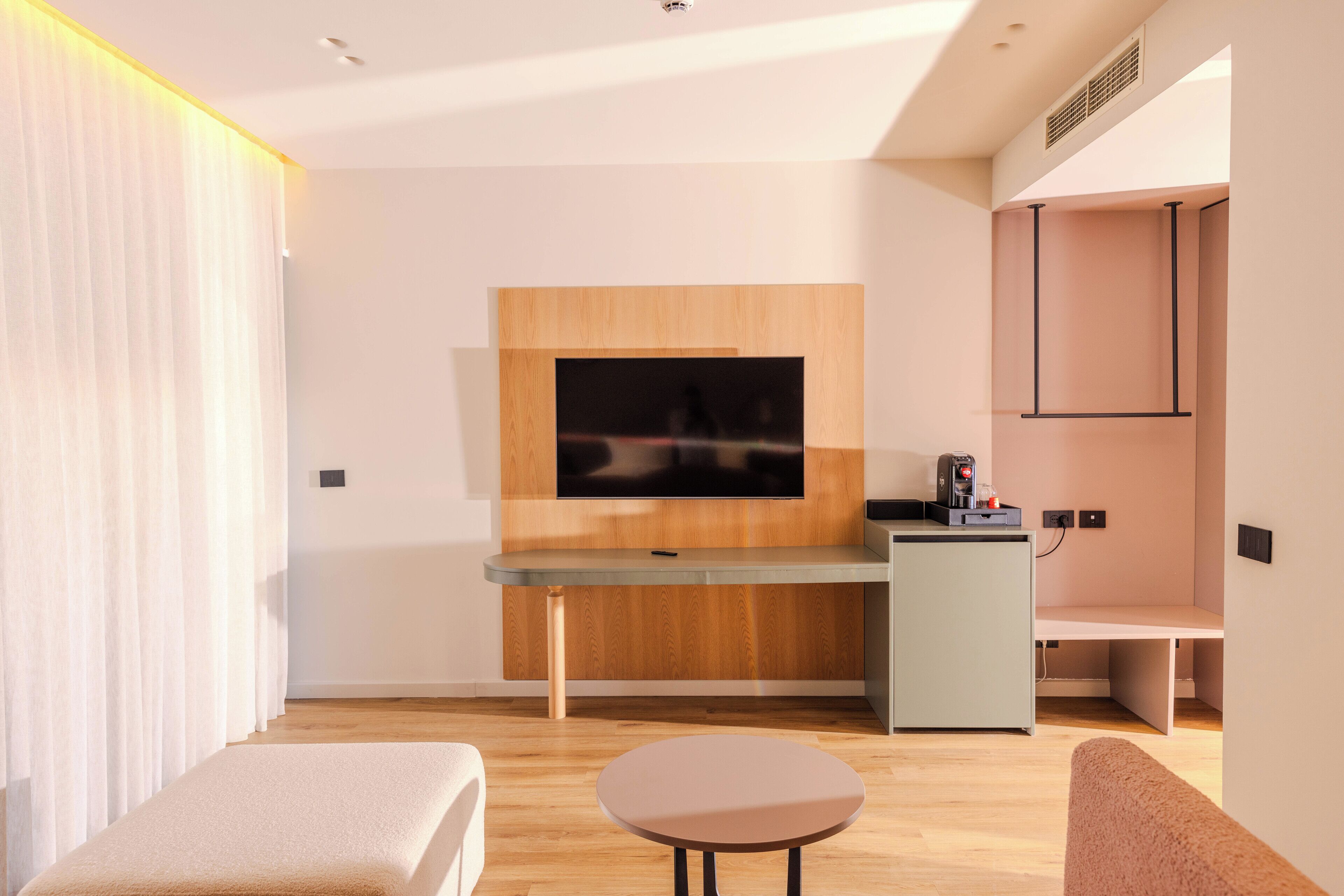 A modern living room with a flat-screen TV mounted on a wooden wall, a small table, and a bench.