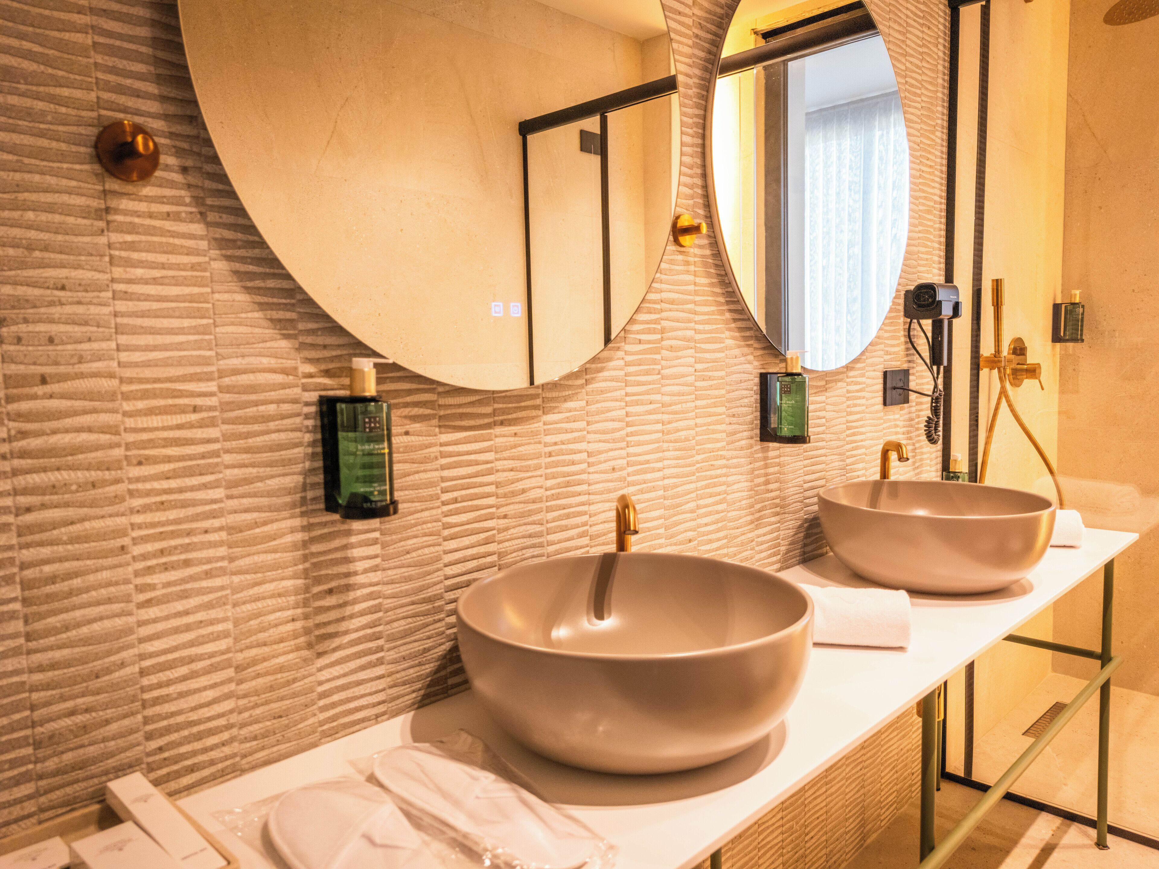 A modern bathroom with two large sinks, a large mirror, and a towel rack.