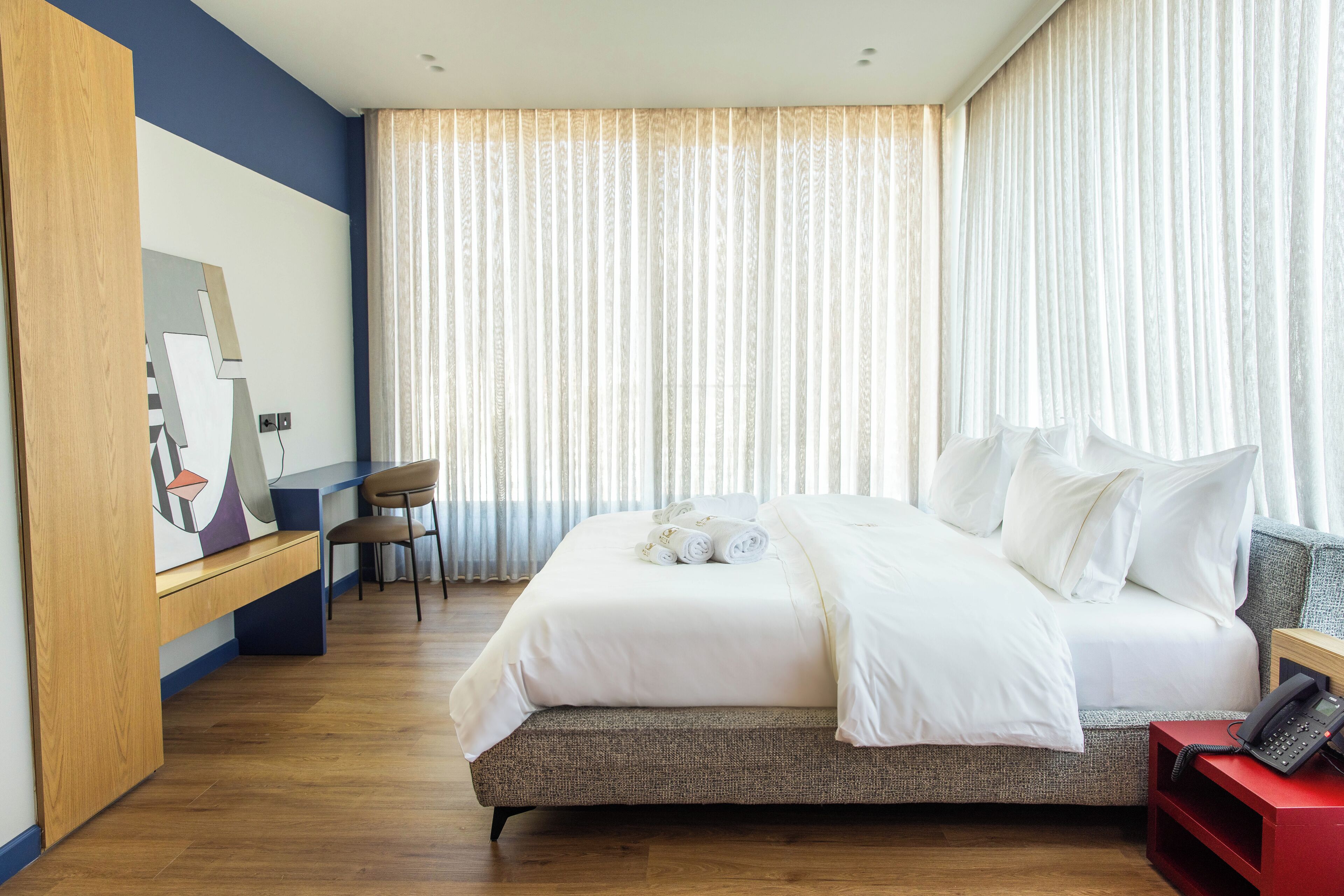 A modern hotel room with a large bed, a desk, and a chair.