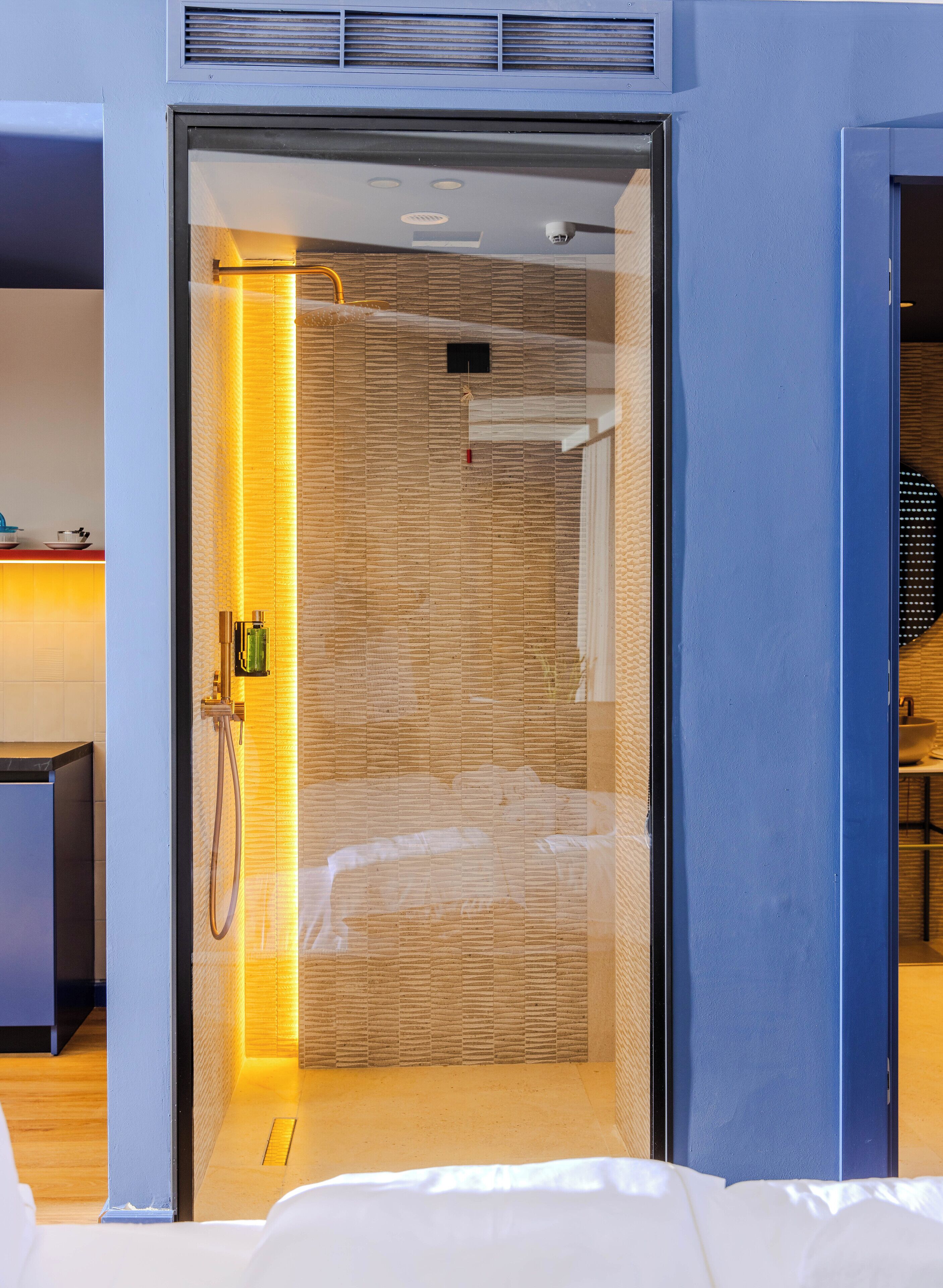 Una habitación de hotel moderna con una puerta corredera que da a una zona de ducha, una cama y una mesita con una taza y un plato.