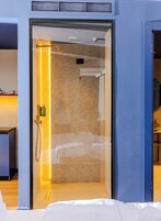 Una habitación de hotel moderna con una puerta corredera que da a una zona de ducha, una cama y una mesita con una taza y un plato.