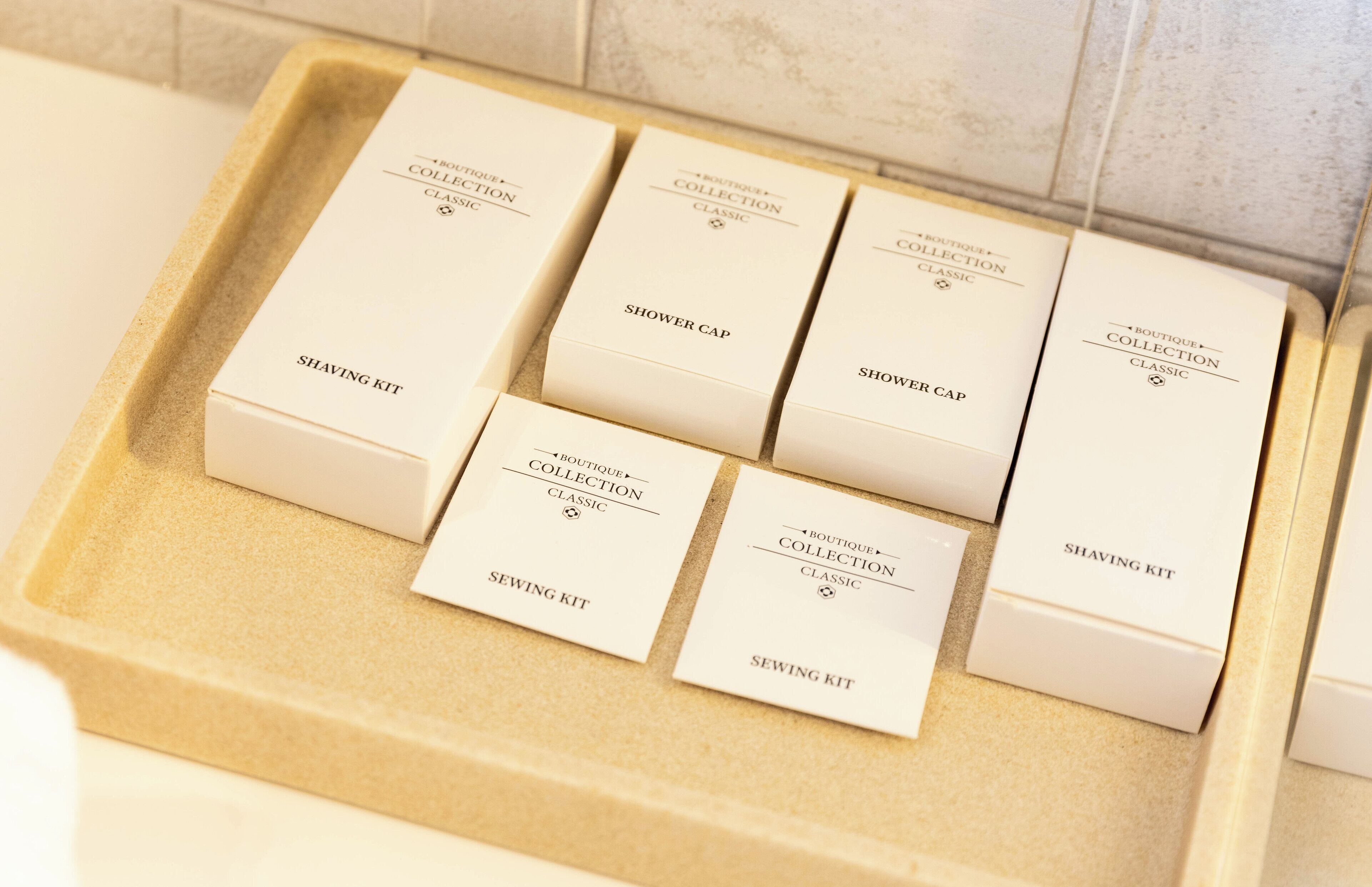 Un vassoio con sei contenitori per articoli da toilette etichettati 'BOUTIQUE COLLECTION CLASSIC', 'COPRIPIEDI' e 'KIT DA CUCIRO'.