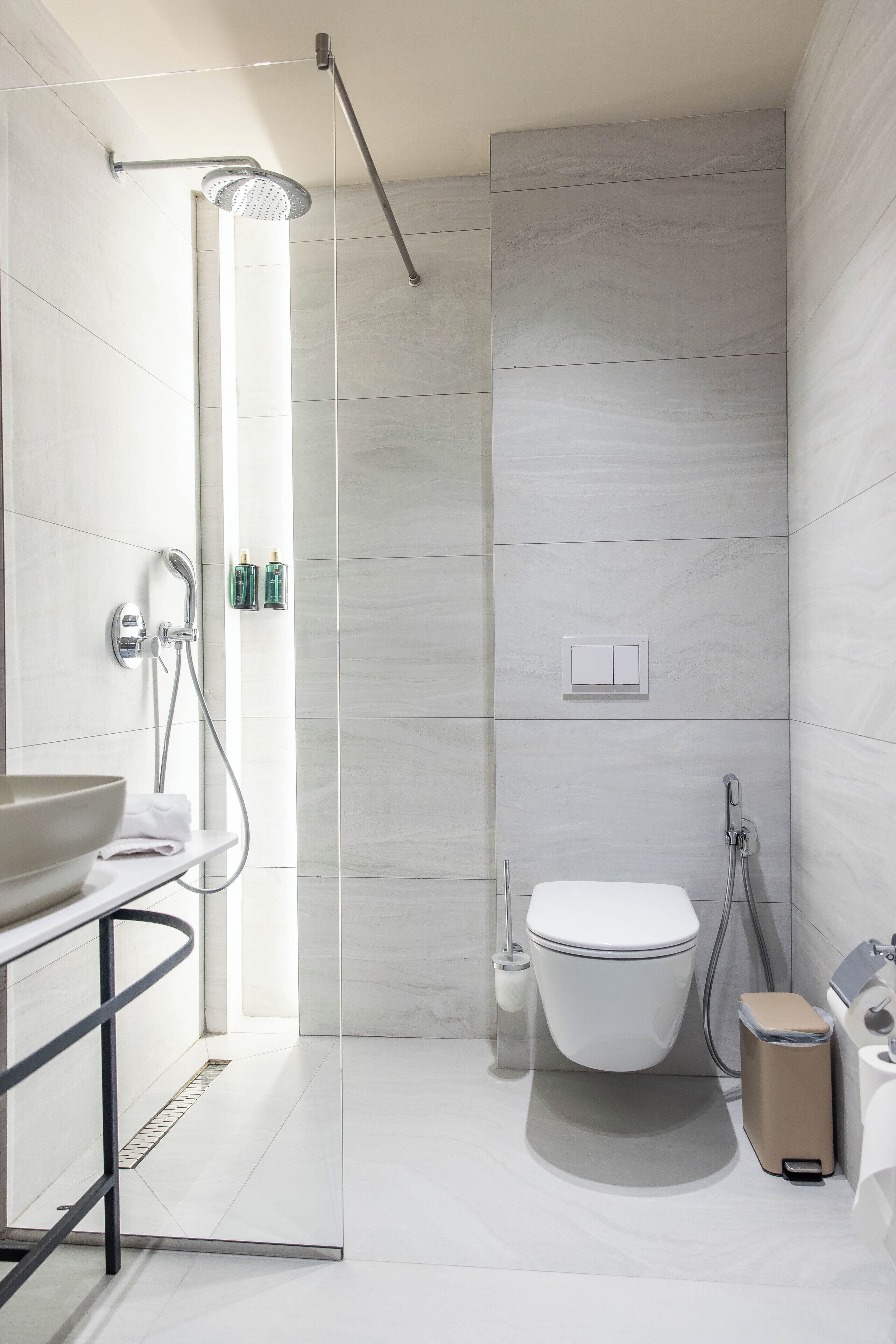A modern bathroom with a glass shower enclosure, a toilet, and a sink with a bowl.