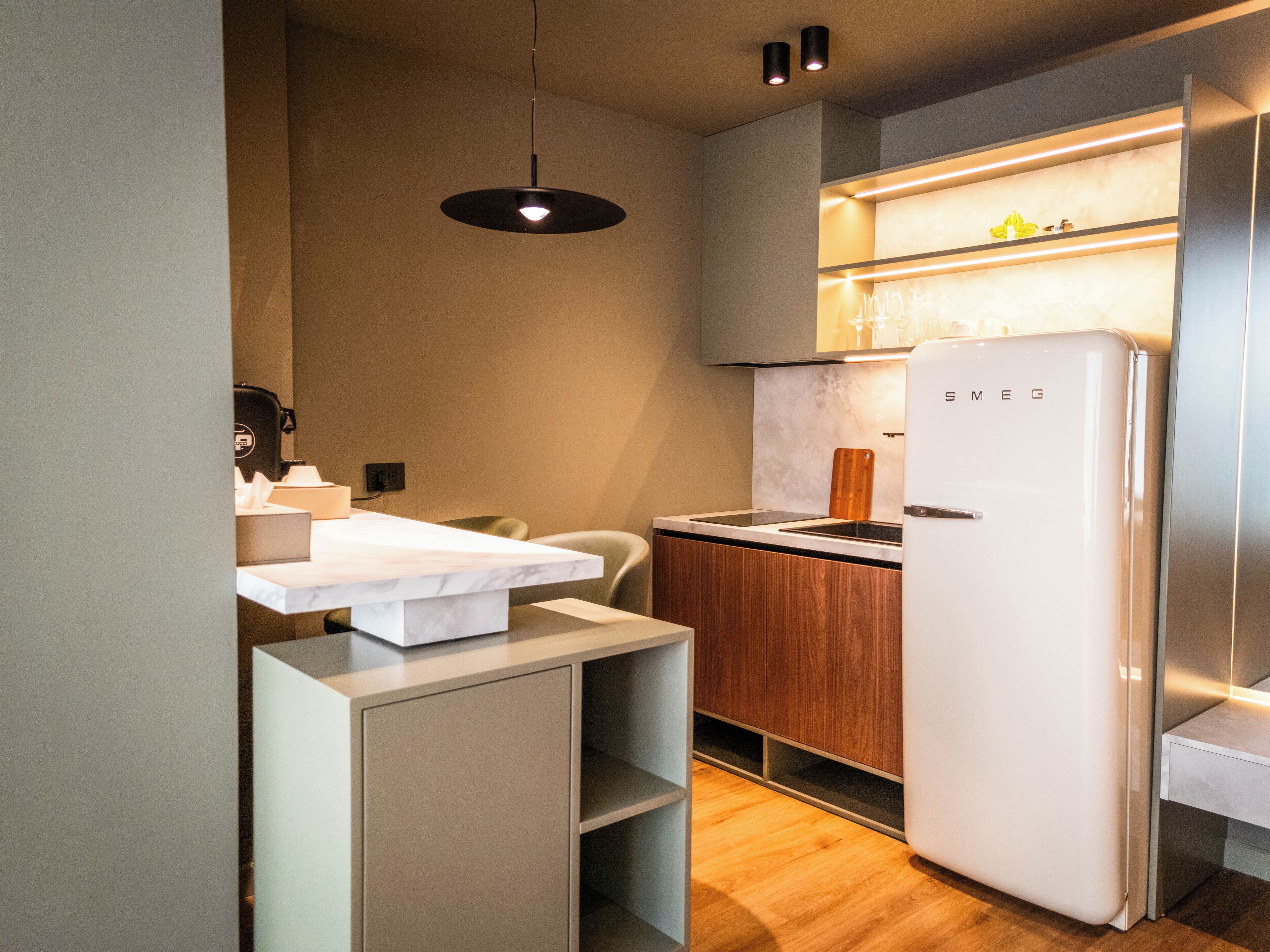 A compact kitchen with a built-in refrigerator, a wooden countertop, and a hanging light fixture.