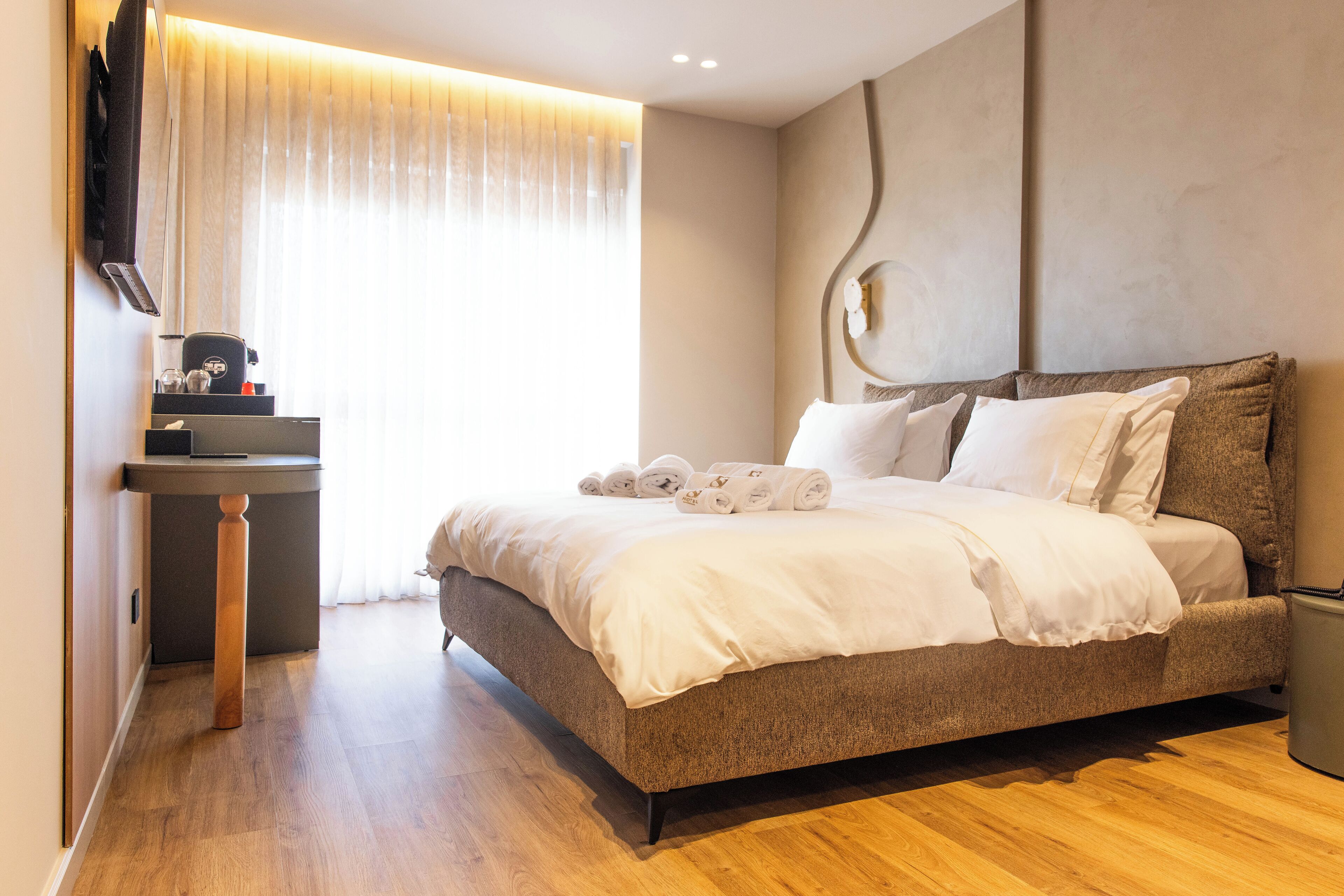 A modern hotel room with a large bed, a bedside table, and a built-in TV.