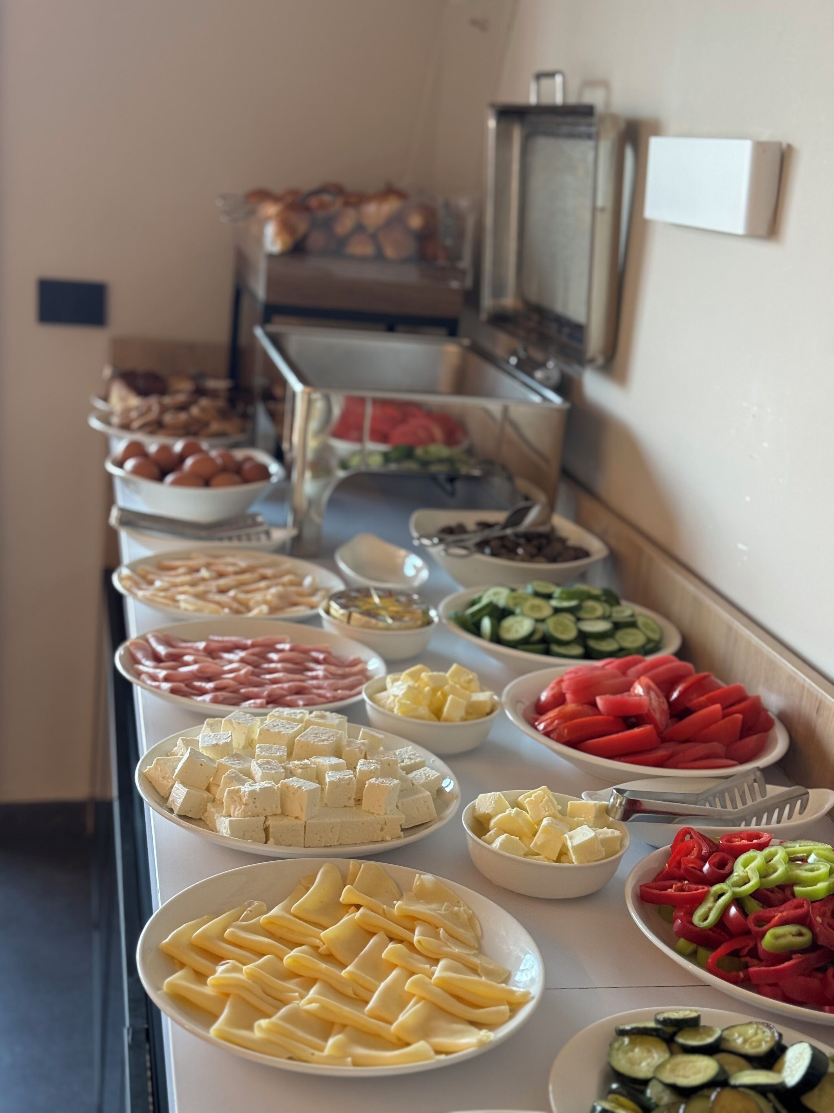 A buffet with various food items including cheese, meats, and vegetables.