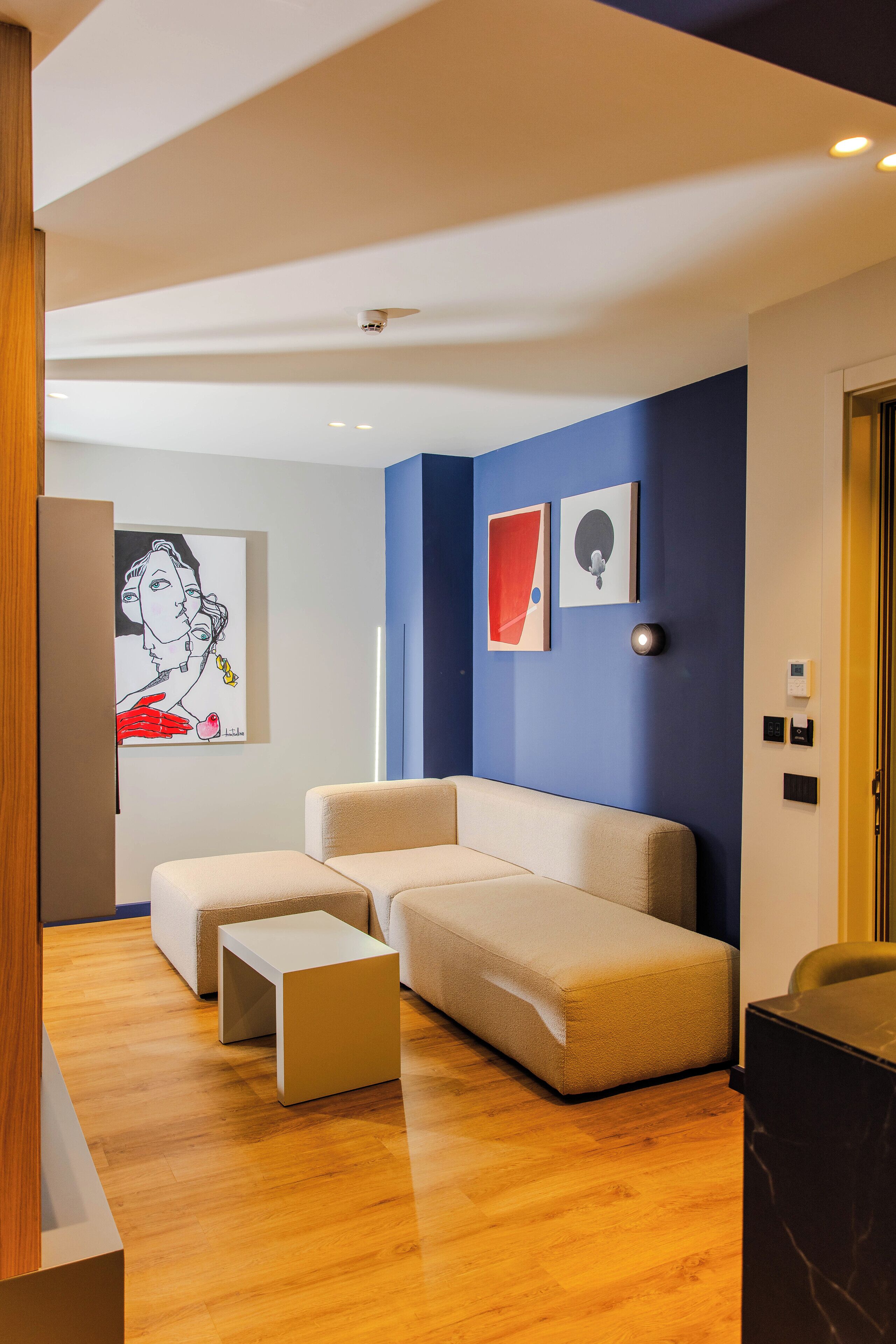 A modern living room with a sectional sofa, a coffee table, and artwork on the wall.