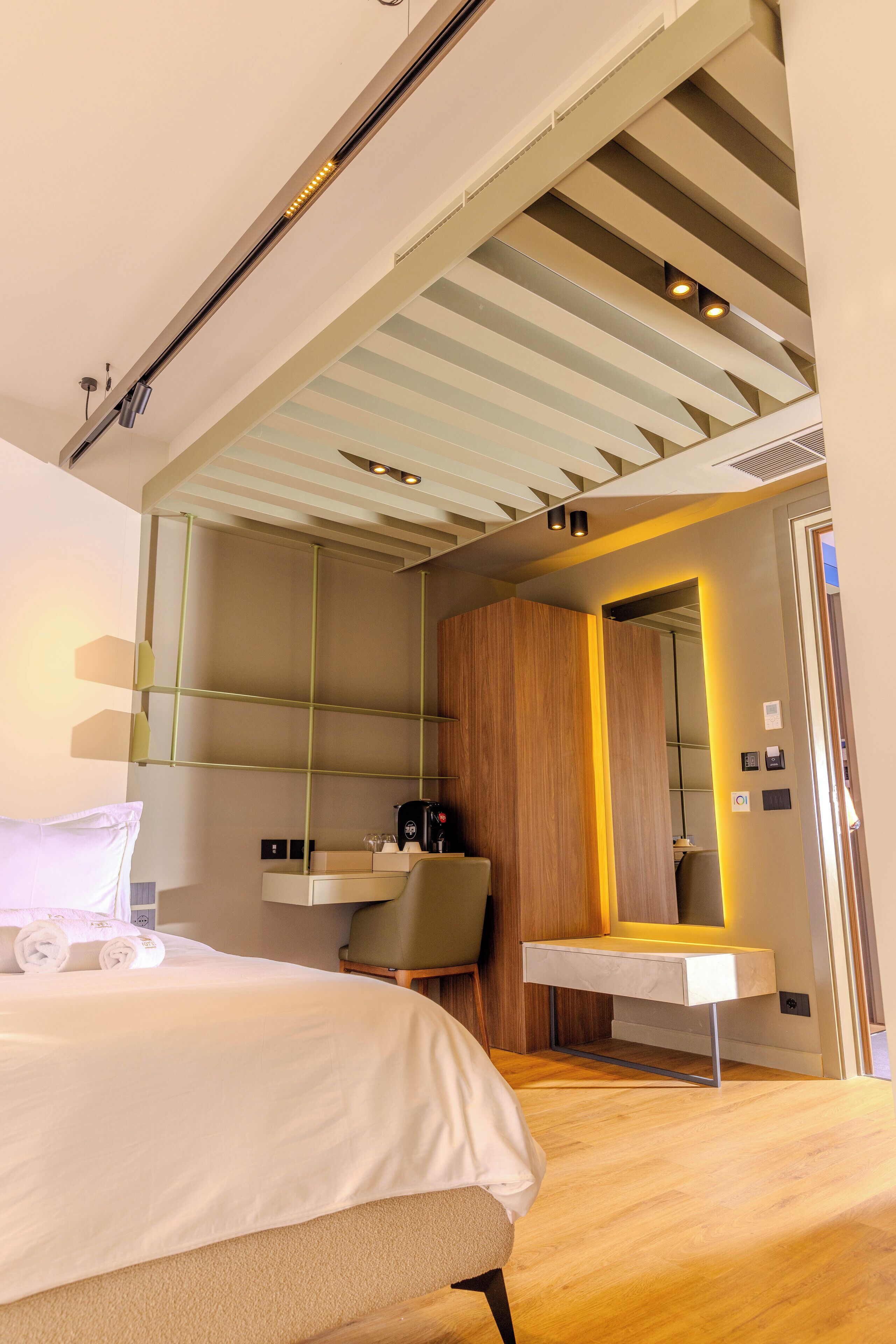 A modern hotel room with a large bed, a desk, and a mirror.