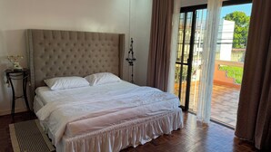 Een slaapkamer met een groot bed, een nachtkastje met telefoon en uitzicht op het balkon.