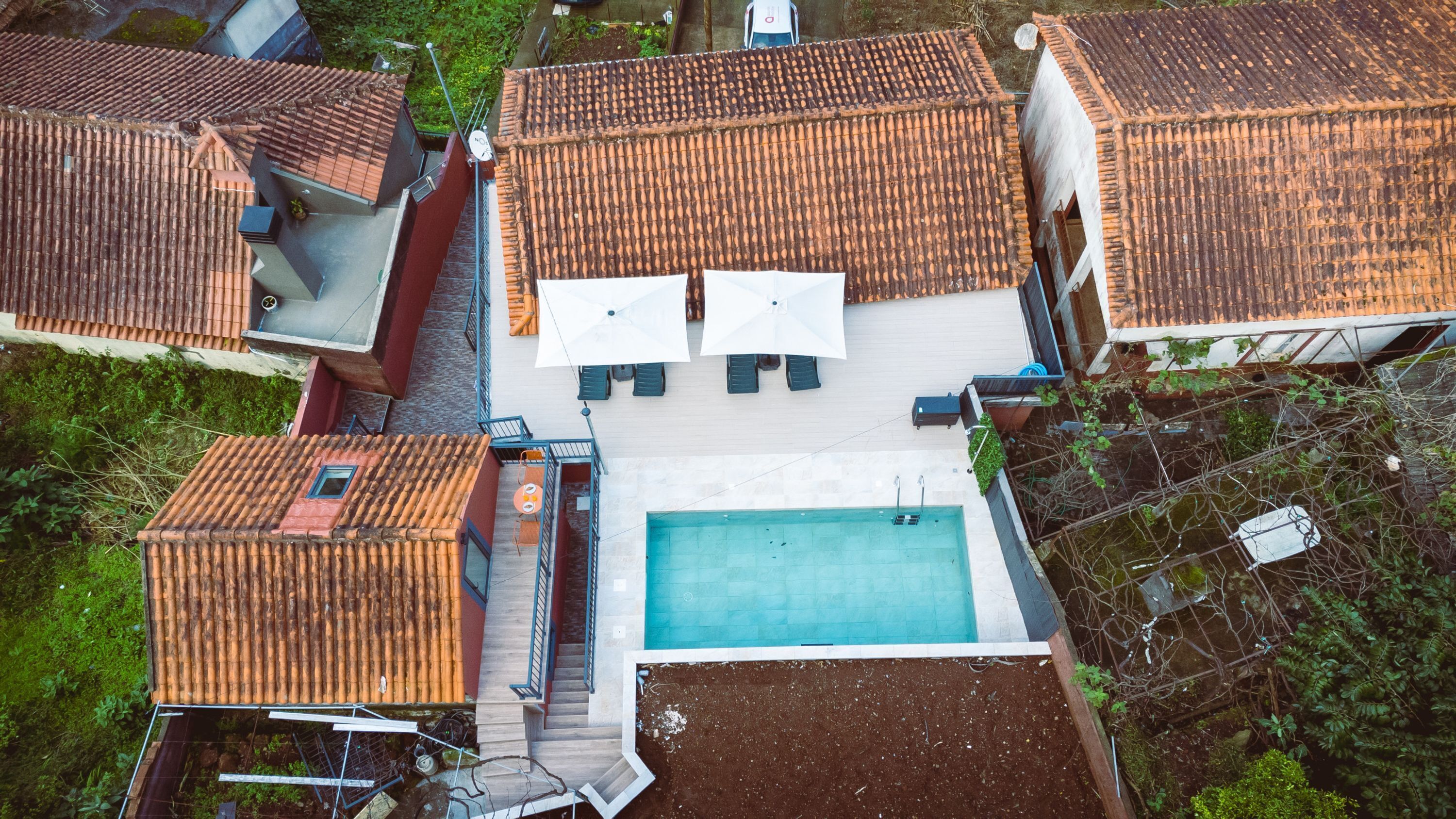 A rooftop pool area with a swimming pool, umbrellas, and lounge chairs.