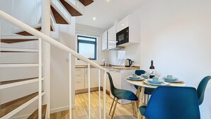 Une cuisine moderne avec un coin repas, un escalier en bois et une vue sur le salon.