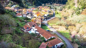 Un village perché sur une colline, avec des maisons à étages, une route sinueuse et une piscine.