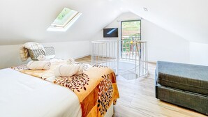 Une pièce aux hauts plafonds, comprenant un lit, une petite table, une chaise et un canapé.