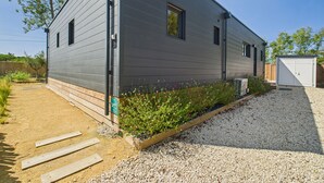 A modern single-story building with a gravel driveway and a garden bed with flowers. - Chalet for 6- Heated swimming pool all year round (Saint-Gilles-Croix-de-Vie)
