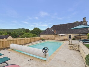 A swimming pool with a control wheel, surrounded by a wooden fence, stone walls, and a view of a hilly landscape. - In the heart of the village, house for 8 with pool (Coly)
