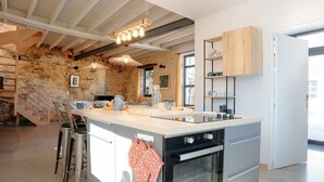 A modern kitchen with a large island, built-in oven, and bar stools. - In the heart of the village, house for 8 with pool (Coly)